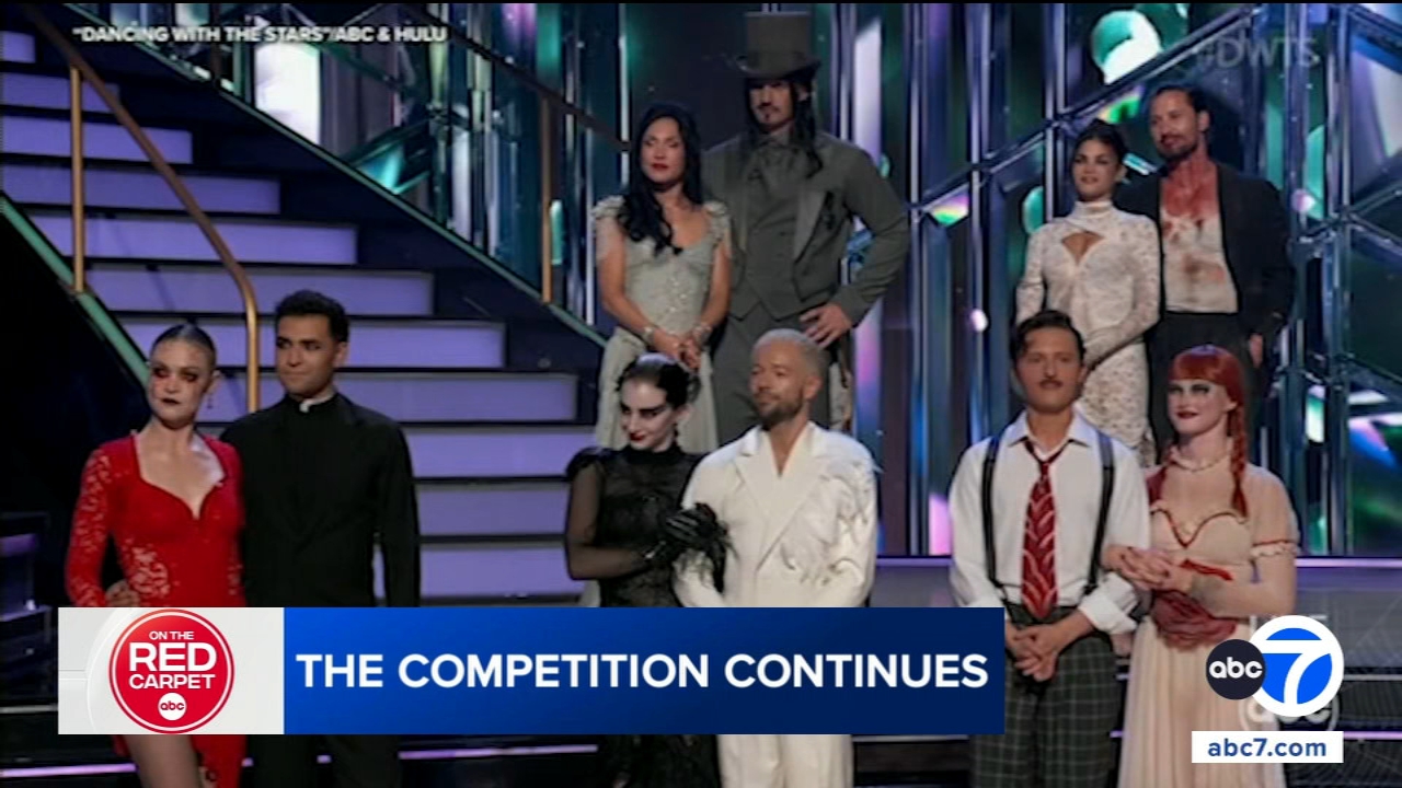 Dancers in elaborate Halloween costumes performing on a brightly lit stage